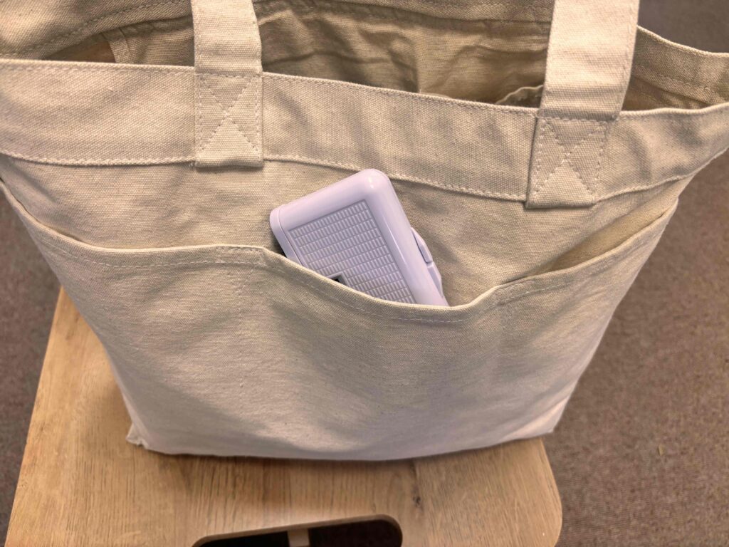 コンパクトオペラグラスをトートバッグのポケットに収めた様子