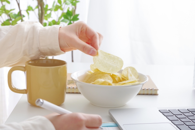 PC作業中にポテトチップスをつまむ女性の手元