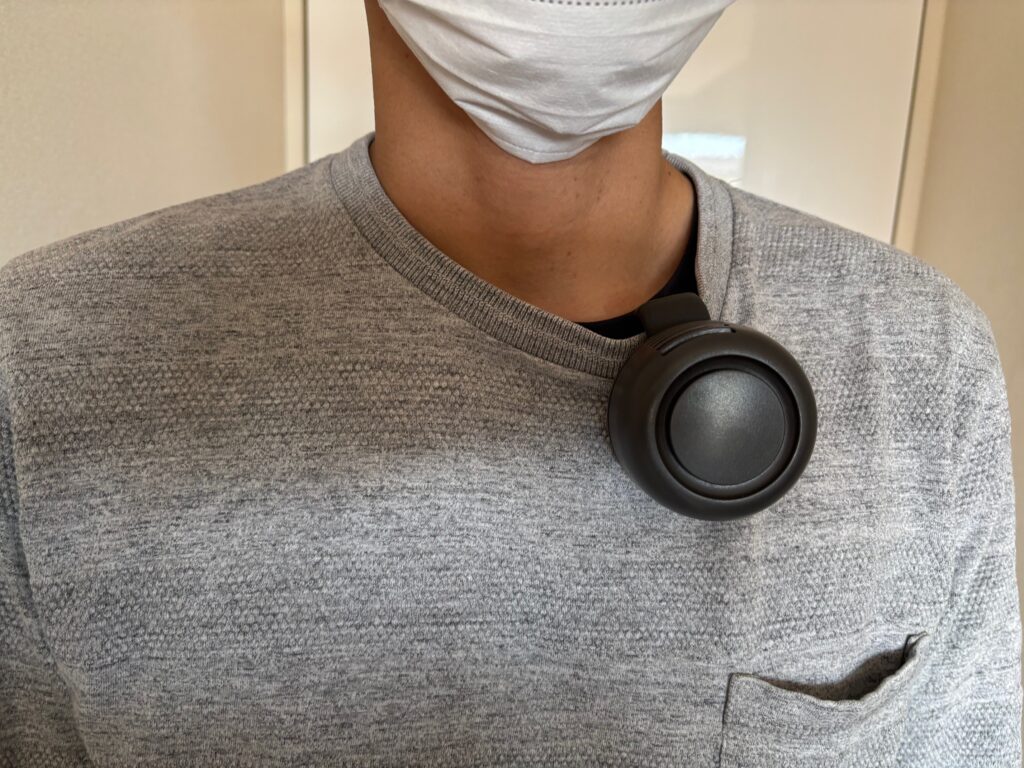 360度回転クリップファンを襟元に浸けている男性