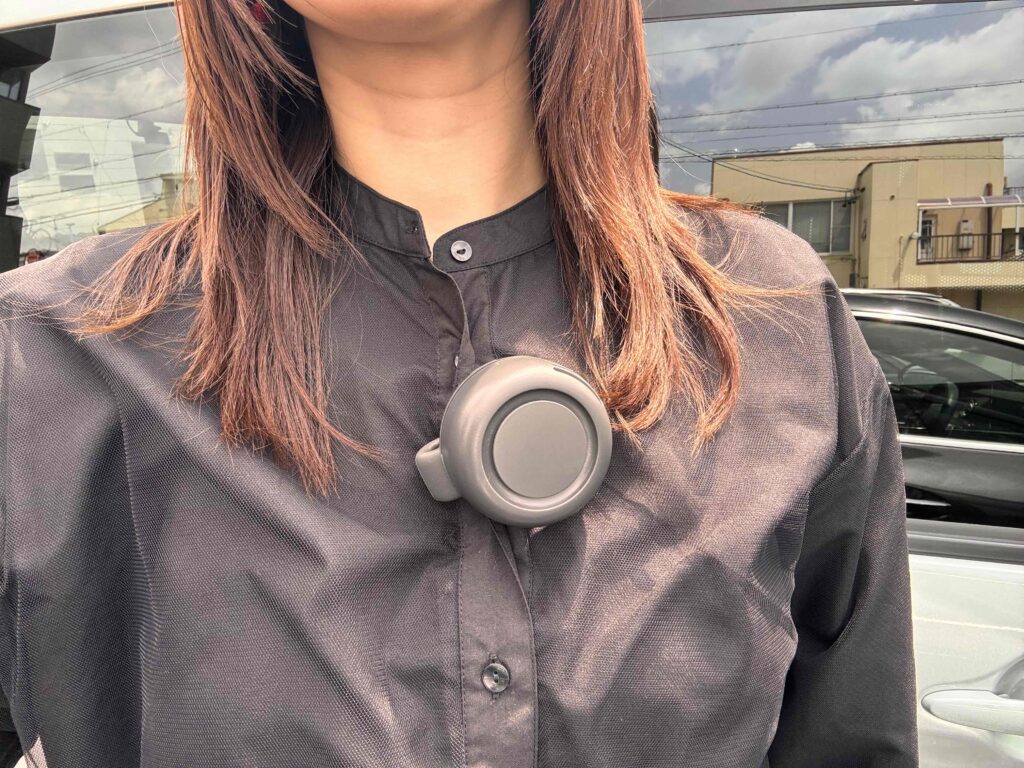 360度回転クリップファンをシャツの胸元に浸けている女性