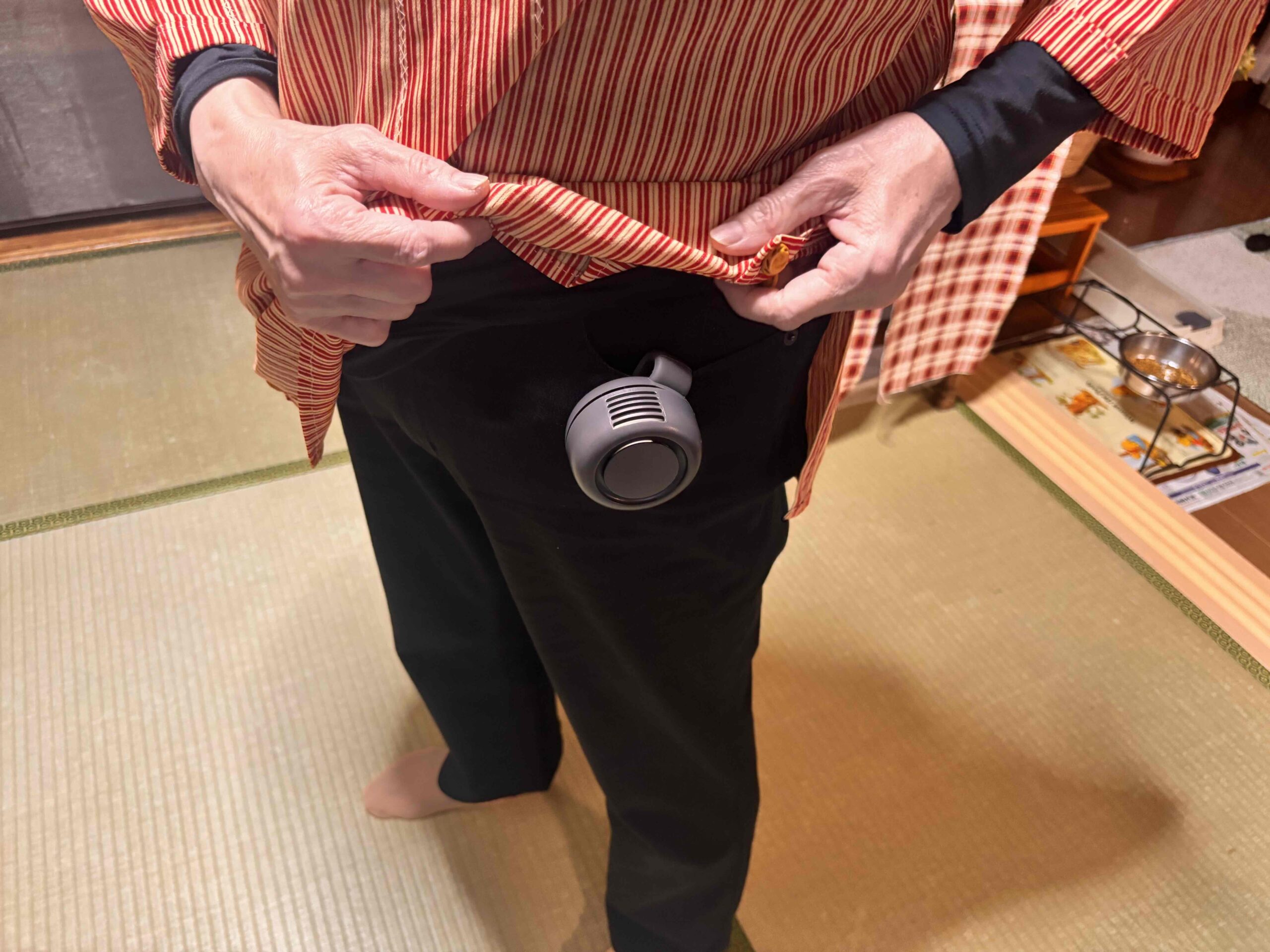 360度回転クリップファンをボトムのポケット部分に取り付けて立っている女性