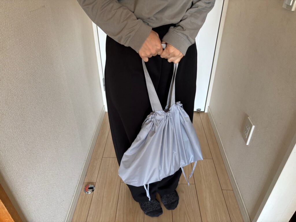 レインカバーにもなる撥水バッグの口を絞り手に持つ女性