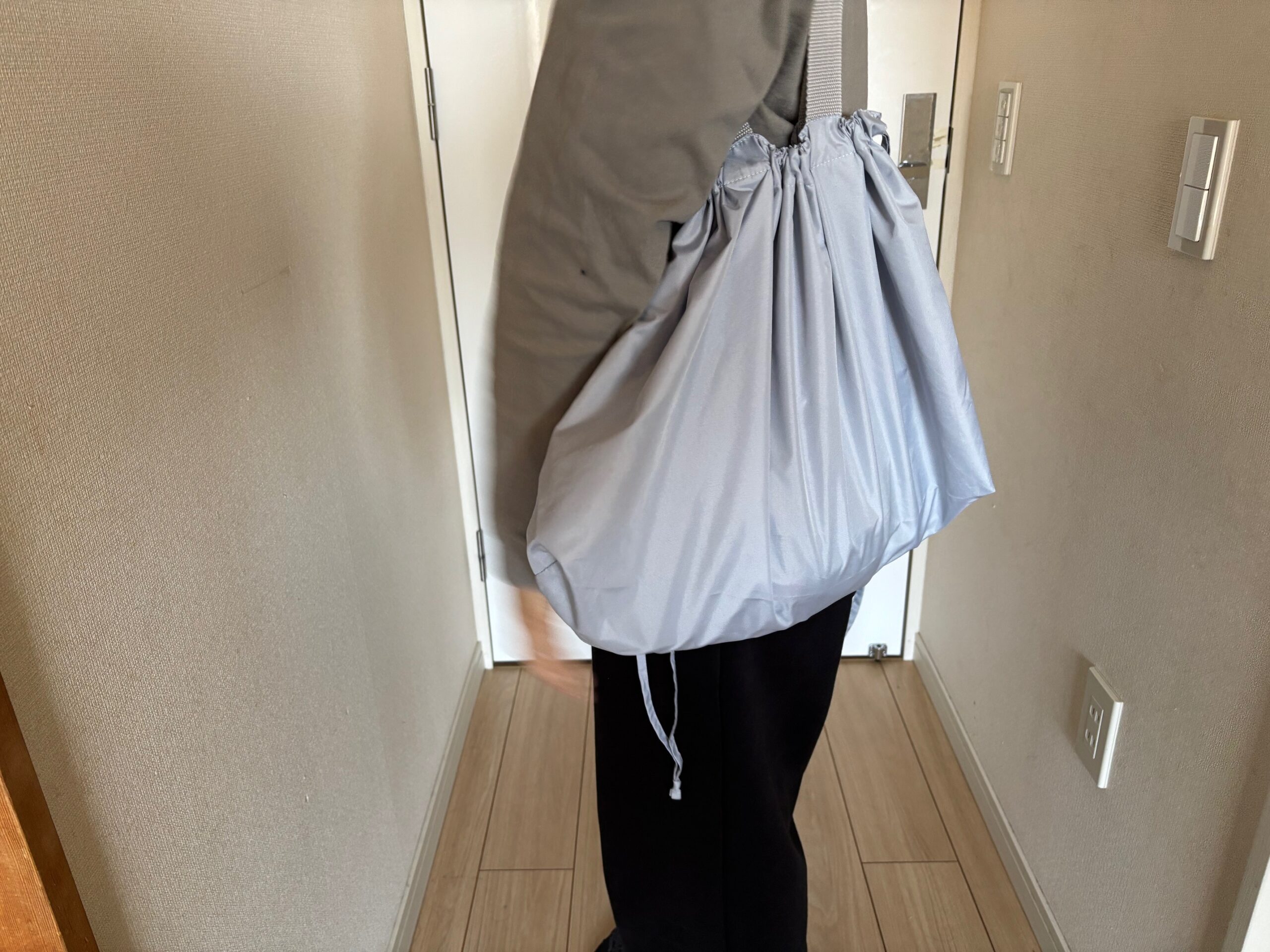 レインカバーにもなる撥水バッグを肩に掛けた女性