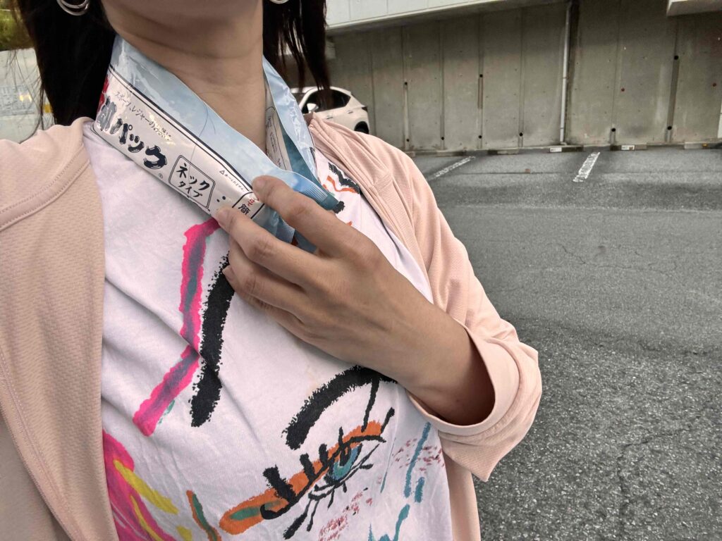 冷却パック ネックタイプを首に巻き外を歩く女性