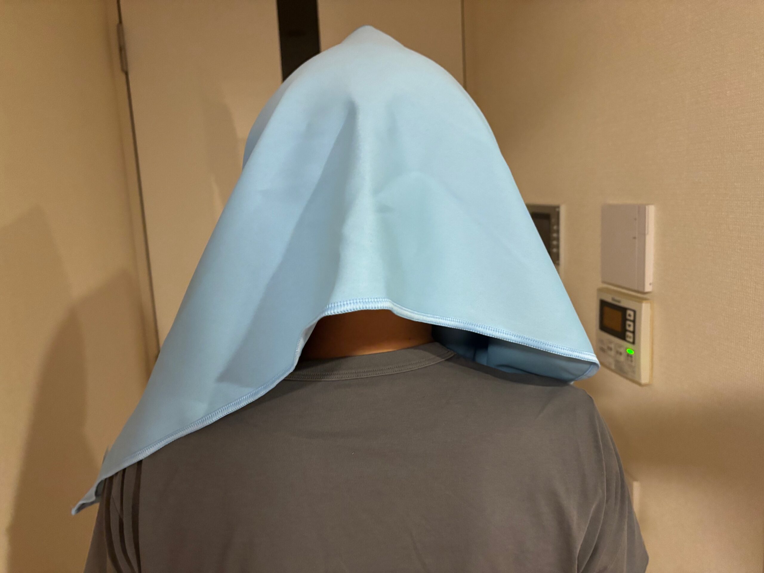 遮光UVカットタオルを頭にかぶせた男性の後ろ姿