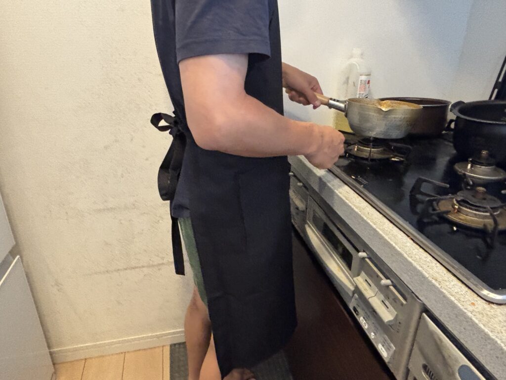 カスタムデザインエプロンを着用し調理している男性