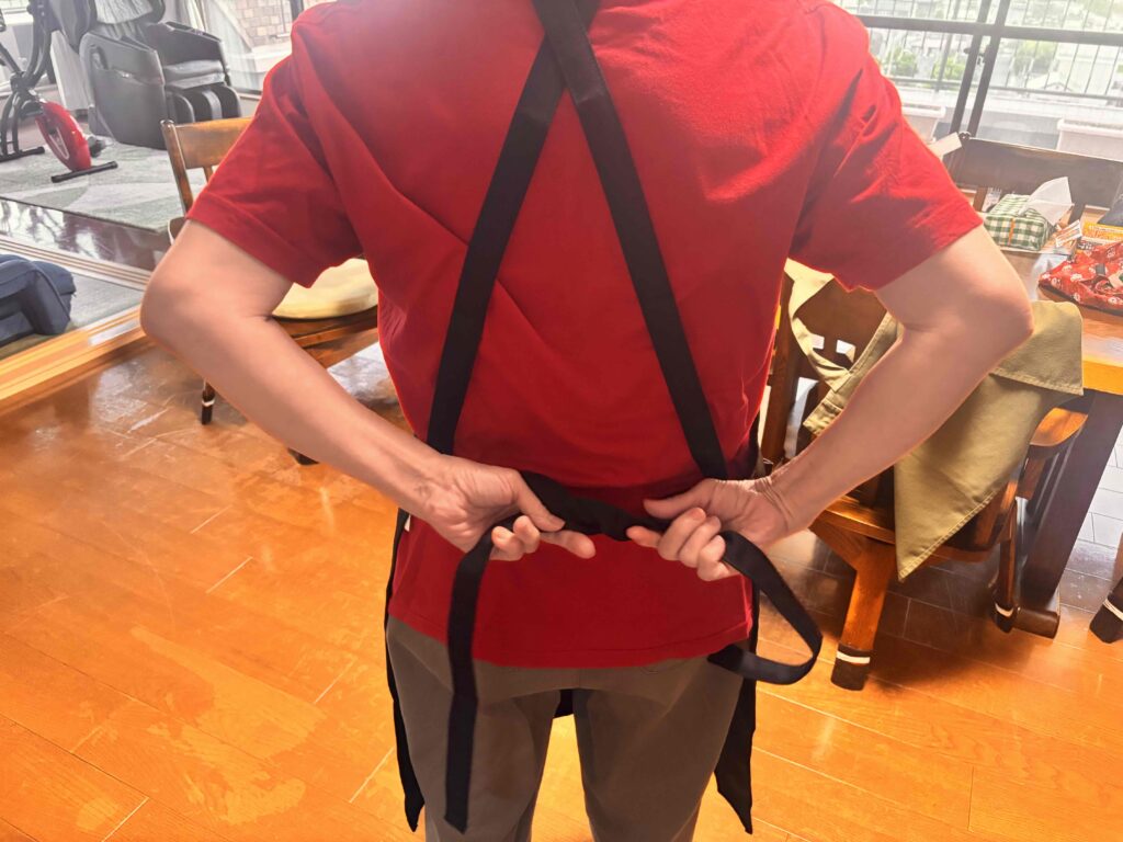 カスタムデザインエプロンのヒモを腰穴に通し結んでいる女性