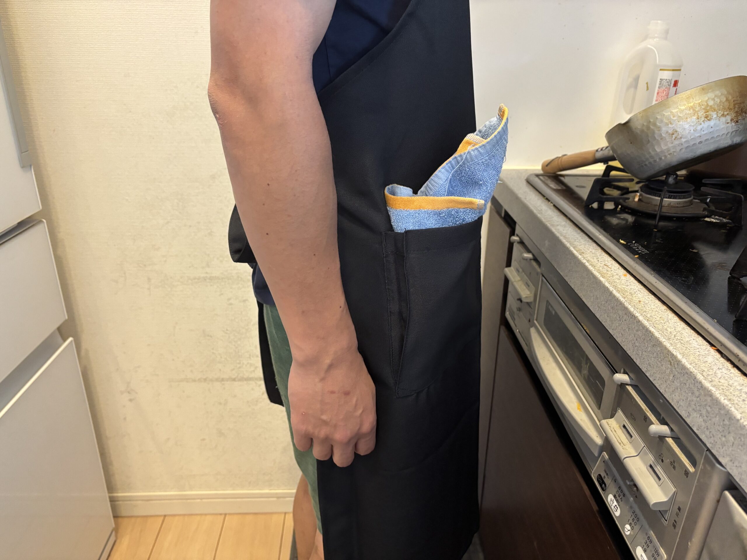 カスタムデザインエプロンを着用し、ポケットにタオルを入れて立っている男性