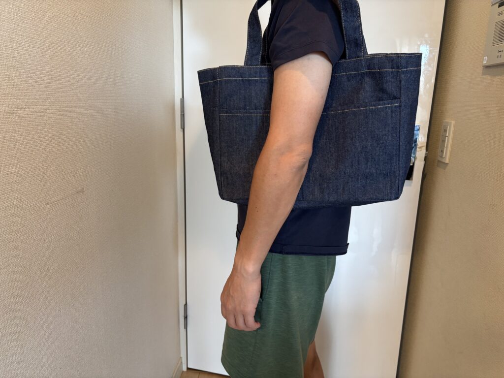 デニムフロントポケットトート　インディゴを肩にかけた男性