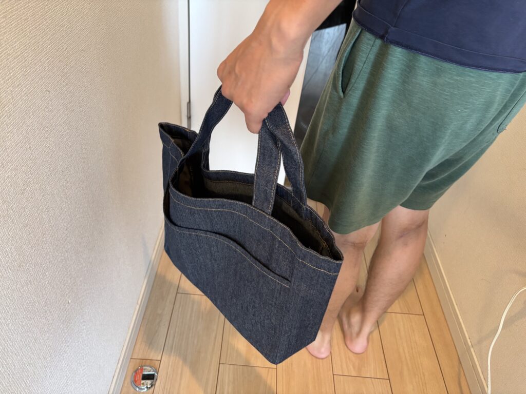 デニムフロントポケットトート　インディゴを手に持った男性の手元