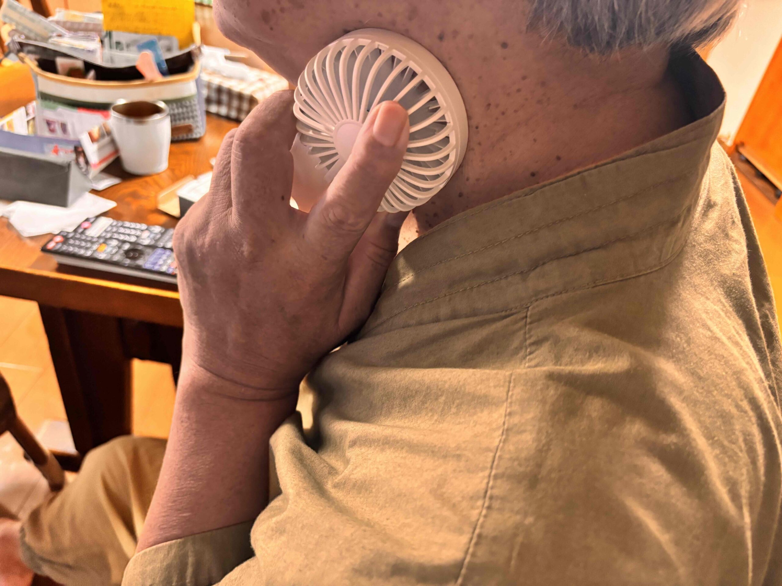 冷却プレートフラットUSBハンデイファン　冷却プレートを首に充てた男性