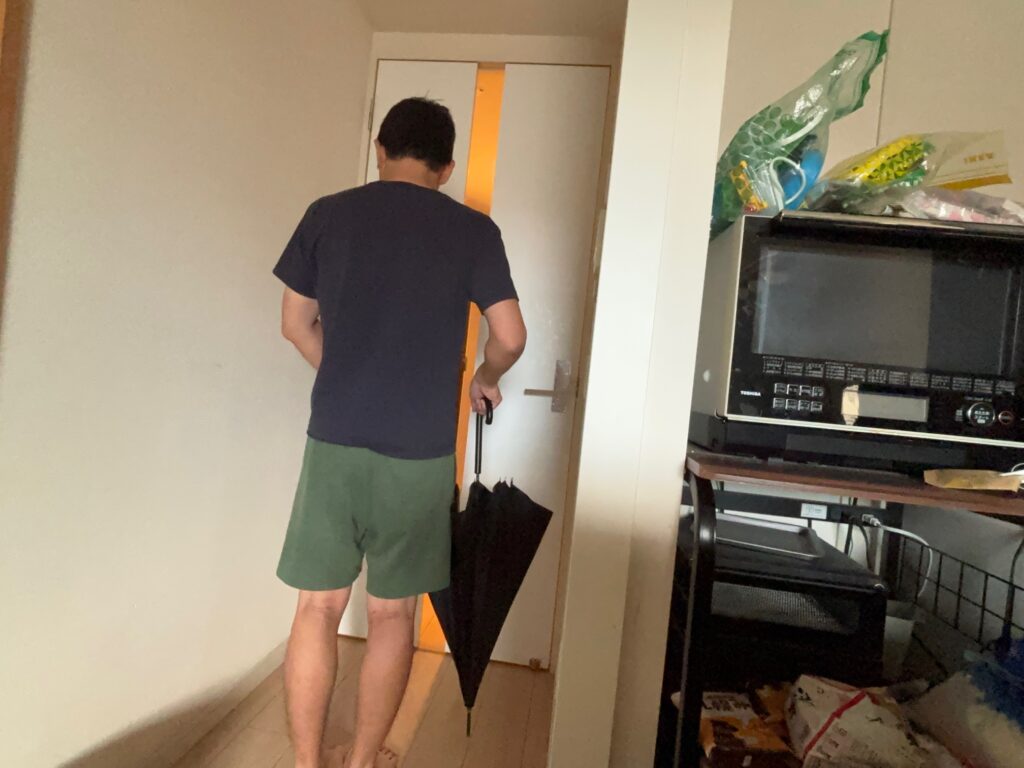 遮光長傘をたたんだ状態で手に持つ男性の後ろ姿
