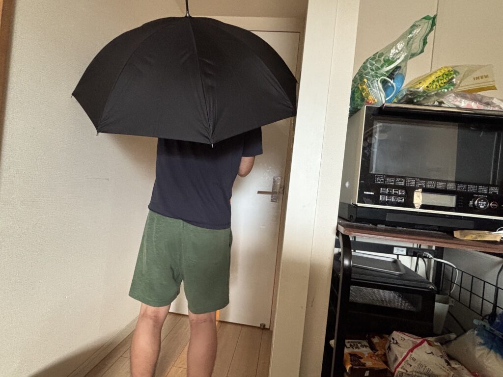 遮光長傘を差している男性の後ろ姿