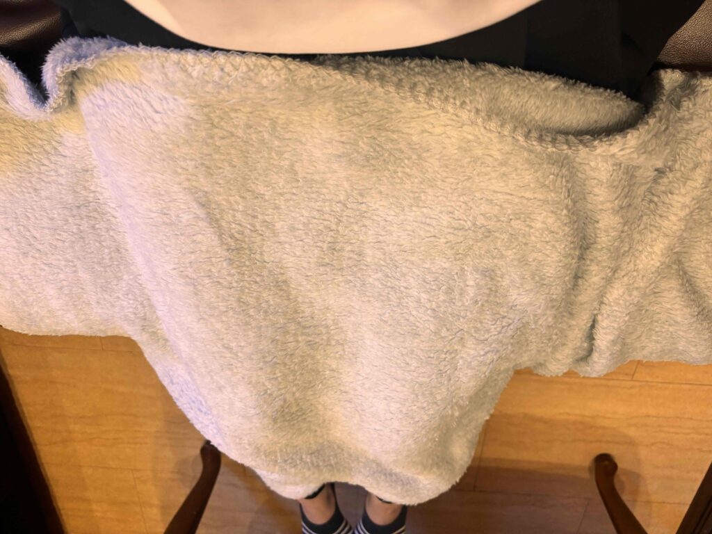 カチオン染めレギュラーブランケット（巾着付）グレーを膝に広げたようす